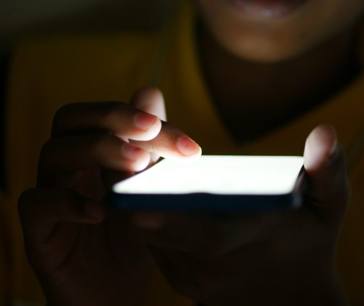 Close up of young man hand using smart phone at night