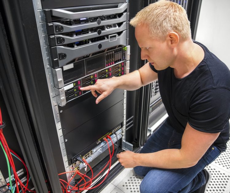 IT Technician Monitors Server On Rack In Datacenter