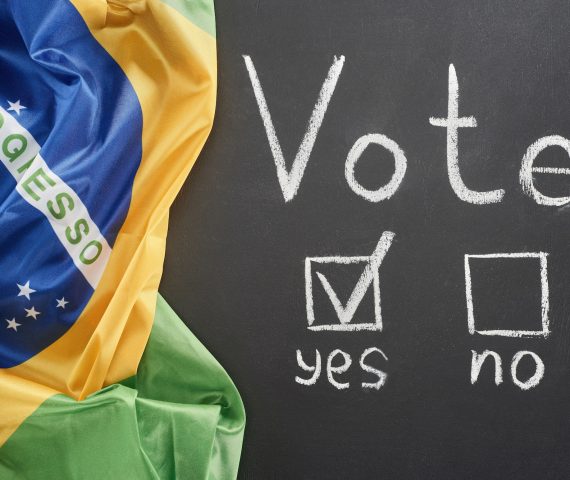 top view of white vote lettering and check mark near yes word on black chalkboard near flag of