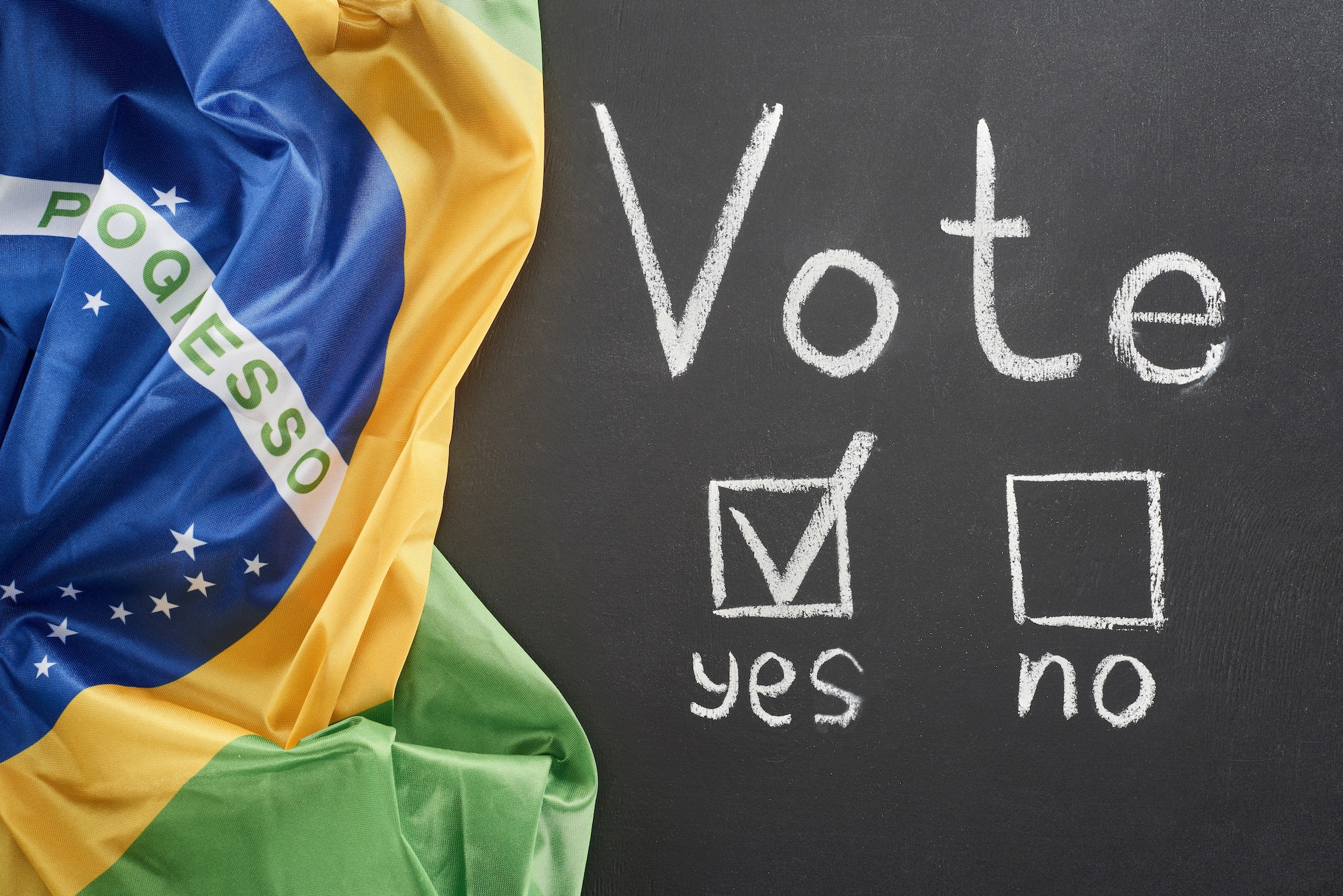 top view of white vote lettering and check mark near yes word on black chalkboard near flag of